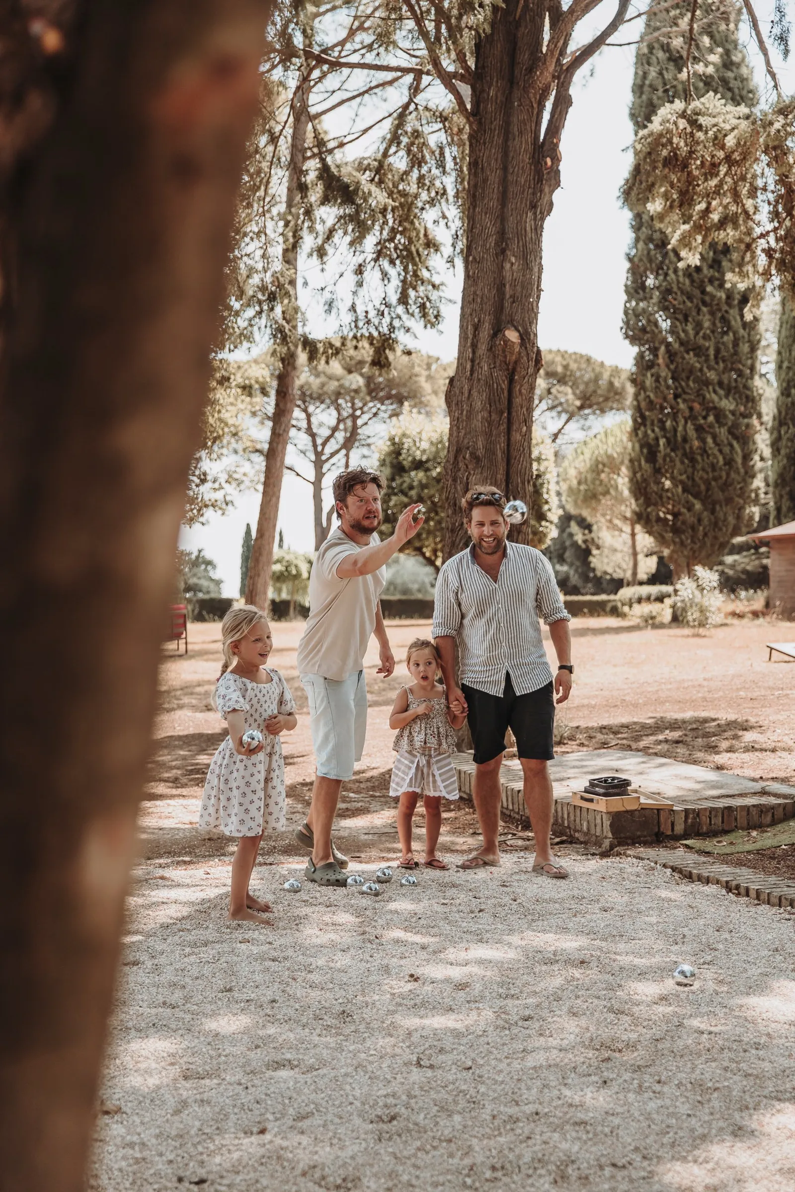 Family playing jeu de boules under the pine trees