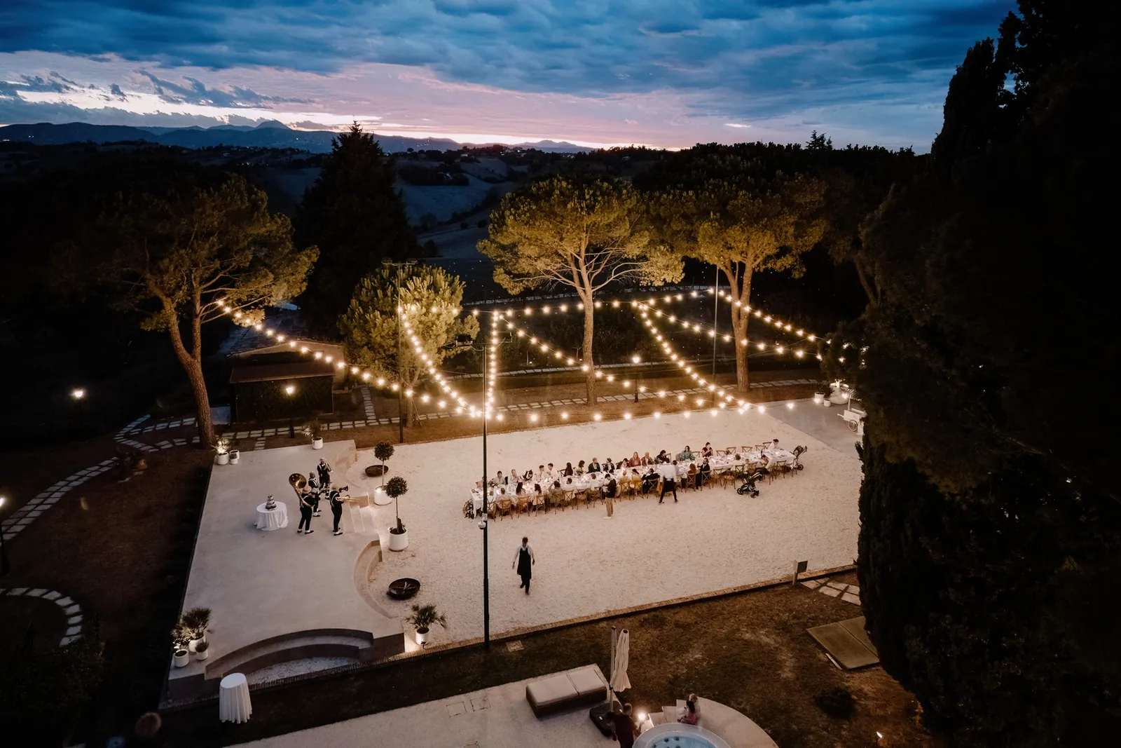 Drone view of the dinner court under string lights at dusk