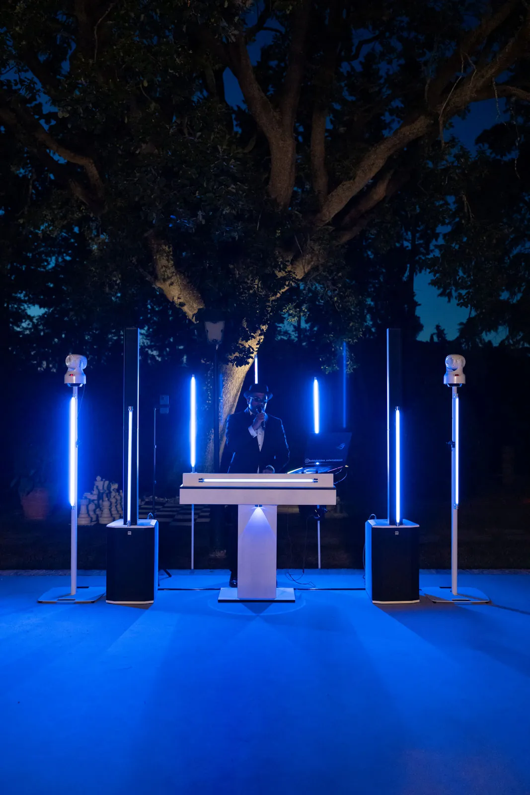 Blau beleuchtetes DJ-Pult unter den Bäumen bei Nacht