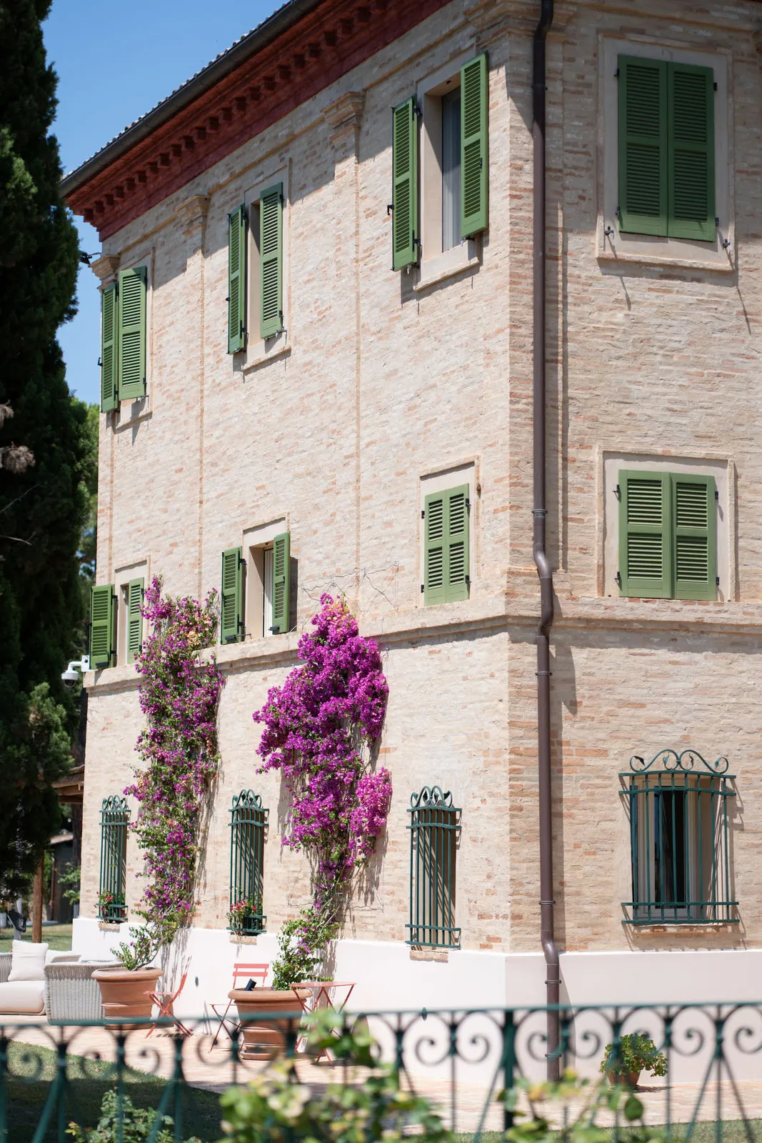 Villa façade with green shutters and pink bougainvillea
