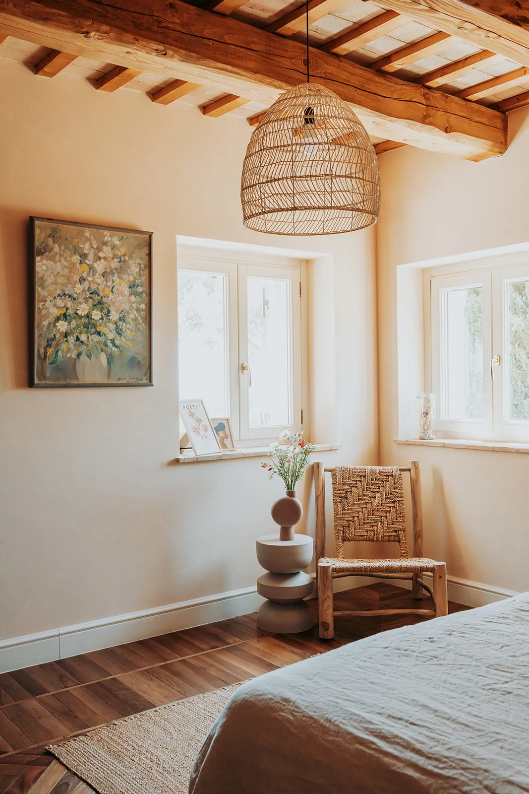 Ein Gemälde eines Blumenstraußes, ein geflochtener Stuhl und frische Blumen unter einer Rattanlampe in The Bouquet