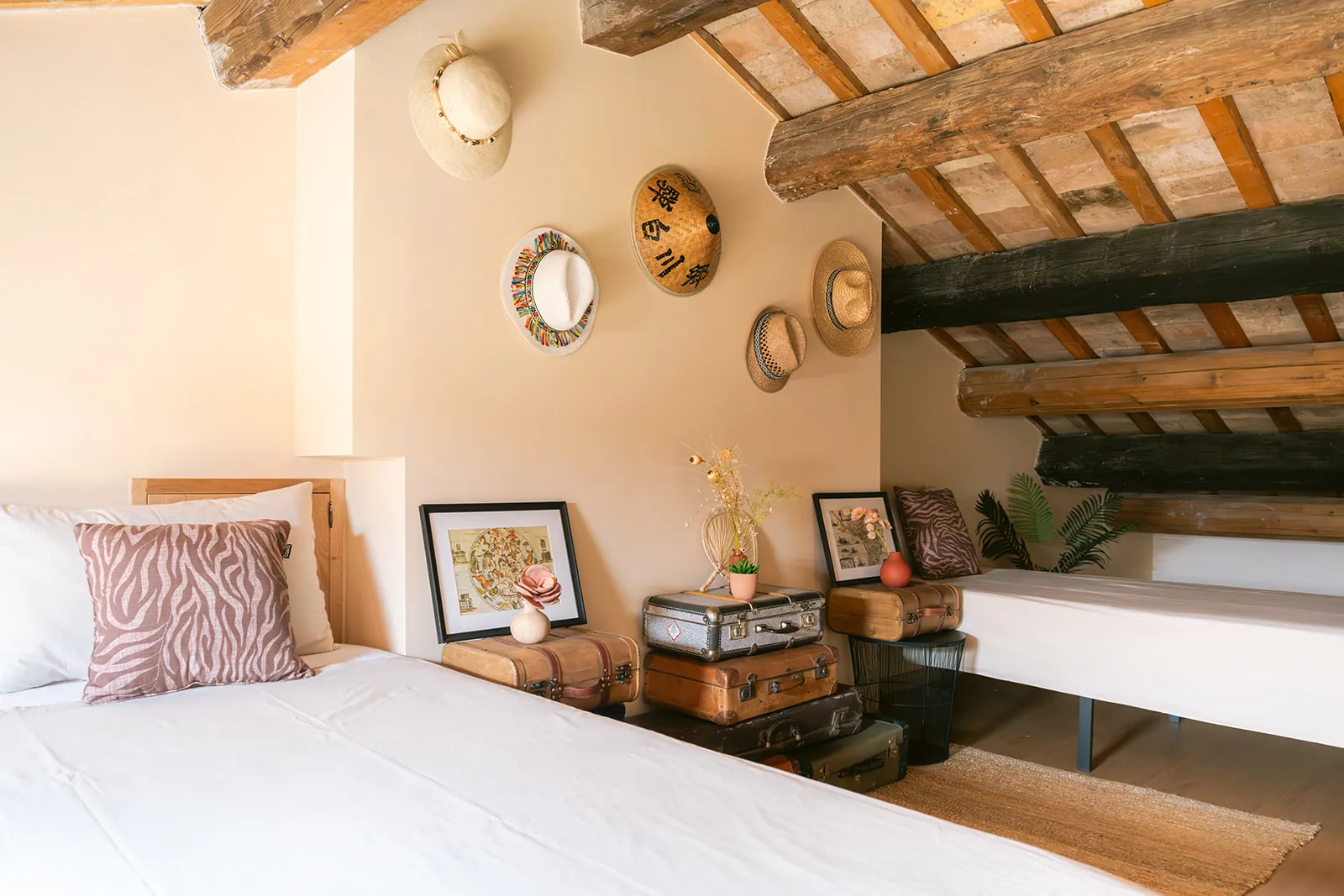 Betten in The Honeymoon neben einer Wand voller Reisehüte und Vintage-Koffer