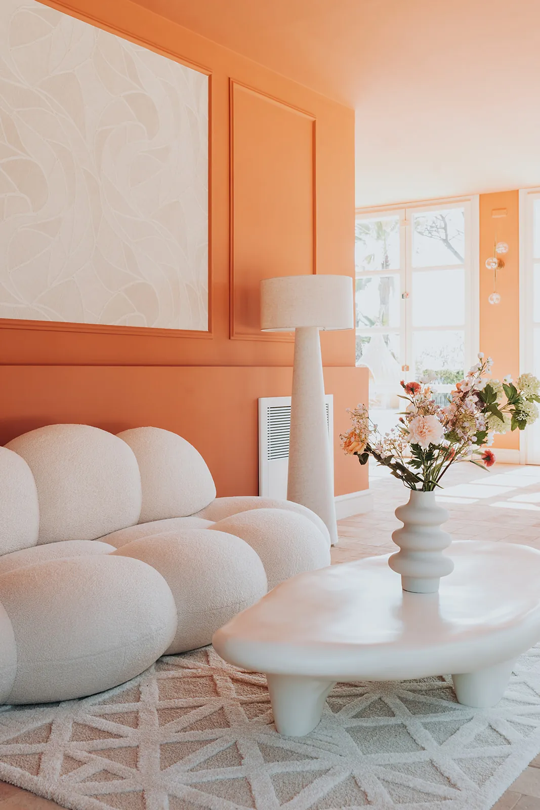 Ein wolkenförmiges Sofa und frische Blumen im Glashaus