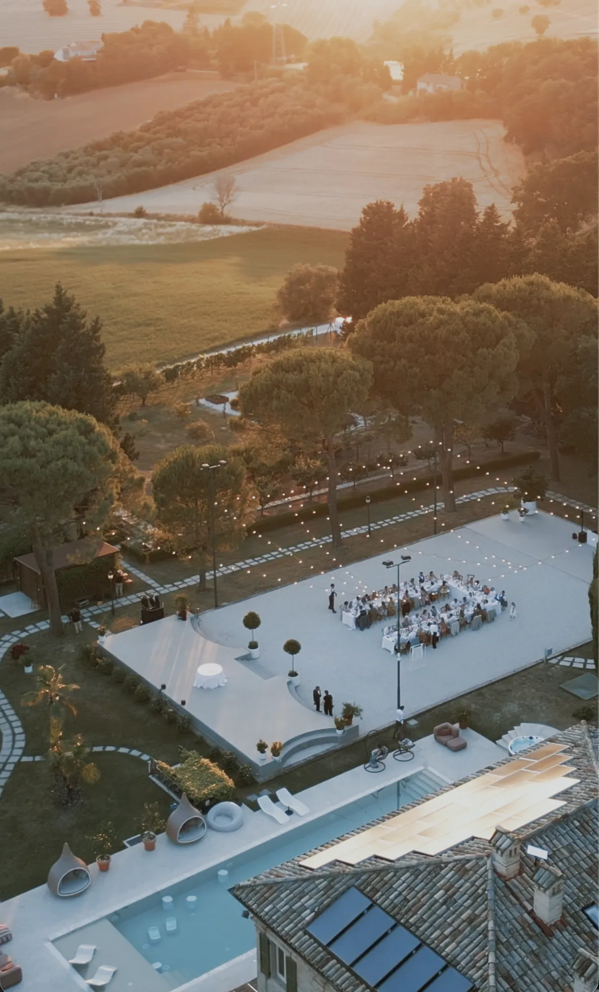 Hochzeitsdinner im Bühne & Dinner-Bereich bei Sonnenuntergang, aufgenommen über dem Dach der Villa