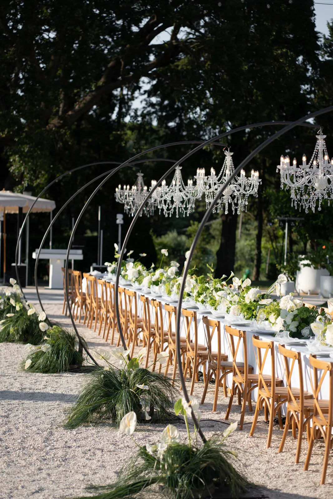 Lange Dinnertafel unter Metallbögen mit Kristallkronleuchtern