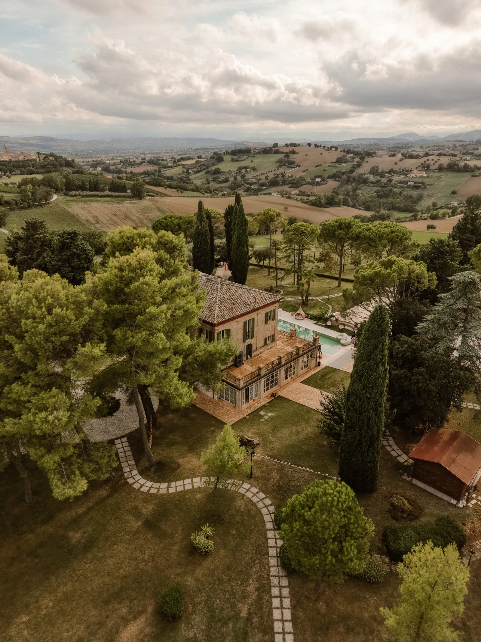 Drohnenblick auf Villa, Pool und Park mit den Hügeln von Le Marche dahinter